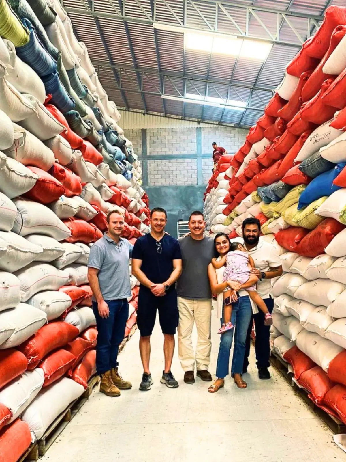 Group of people stood between walls of coffee sacks in Honduras