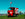 Red solar and wind powered tuk tuk coffee car with Mozzo logo against sunny blue sky