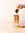 Hand from off screen pouring Mozzo coffee espresso shot into a glass with caramel sauce dripping down it with broken biscuits on a kitchen counter top