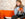 Girl sat on orange sofa with orange coffee mug reading a magazine
